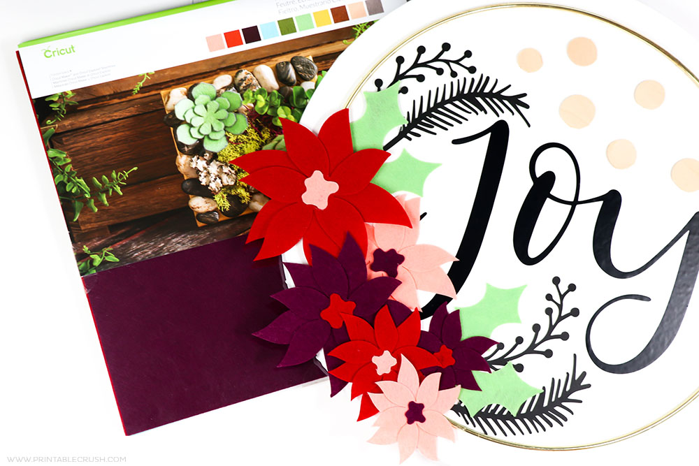 Cut out felt, basswood, vinyl, and paper to make this gorgeous Canvas Christmas Hoop Wreath.